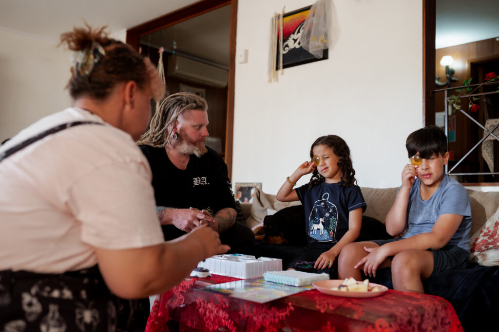 Foster carers and young children sit together, relaxed and playing a game.